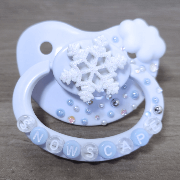 a white snow themed paci with a cloud and snowflake decoration