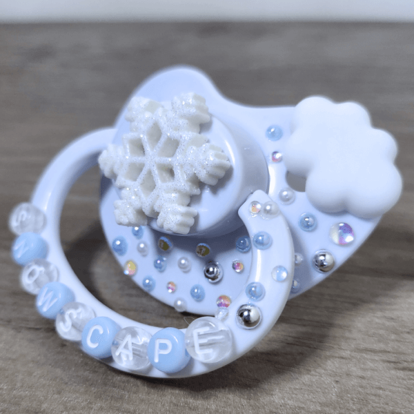 a white snow themed paci with a cloud and snowflake decoration